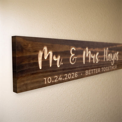 Close-up of the carved letters on the Mr. & Mrs. Hayes sign, natural pine inside the cuts against the stained grain