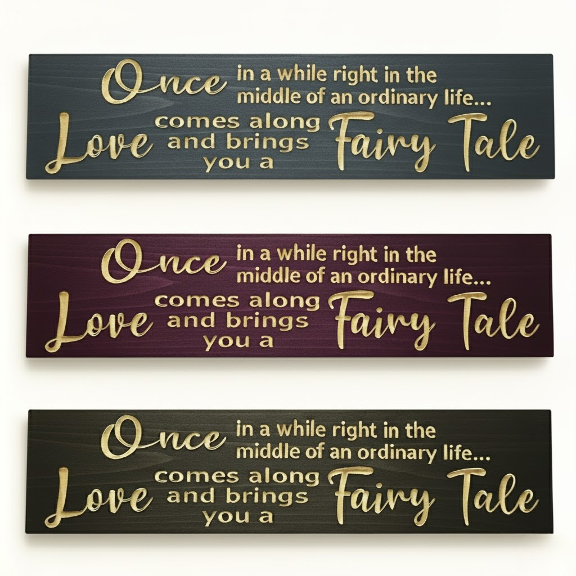 Three color variations of “Once in a while love brings you a fairy tale” carved wooden signs — multiple finishes including black, burgundy, and gray tones.
