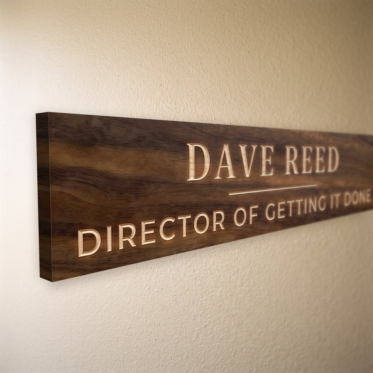 Close-up of the carved letters on the Dave Reed sign, natural pine inside the cuts against the stained grain