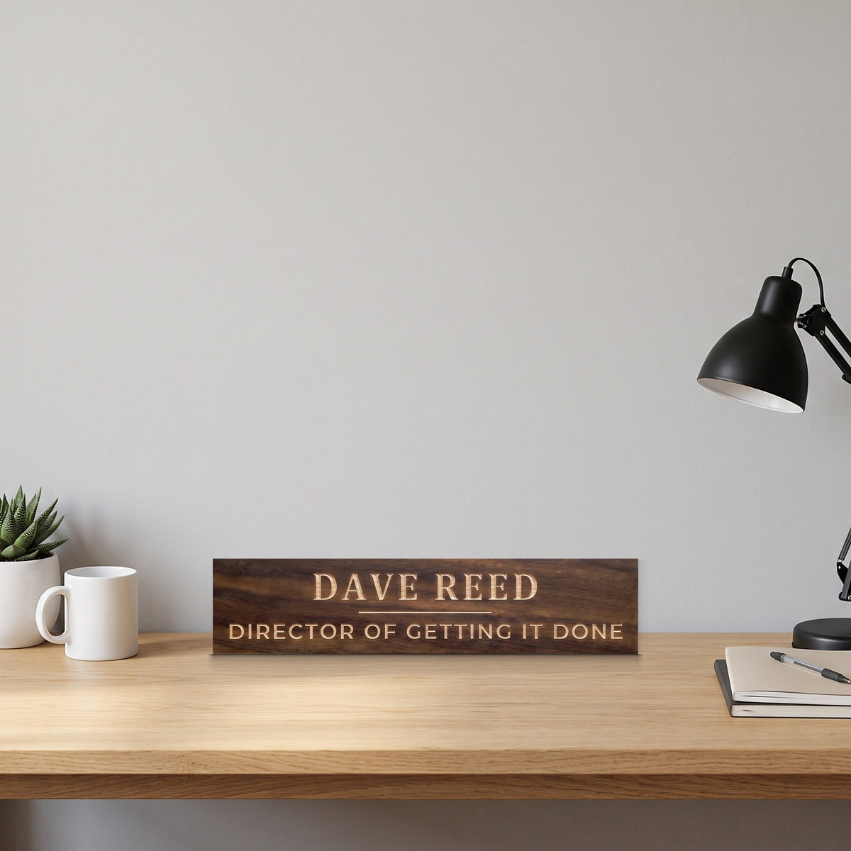 Dave Reed personalized wood nameplate standing on an oak office desk beside a succulent, a coffee mug and a desk lamp