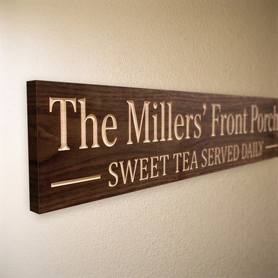 Close-up of the carved letters on the The Millers' Front Porch sign, natural pine inside the cuts against the stained grain