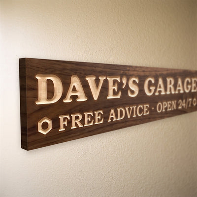 Close-up of the carved letters on the Dave's Garage sign, natural pine inside the cuts against the stained grain