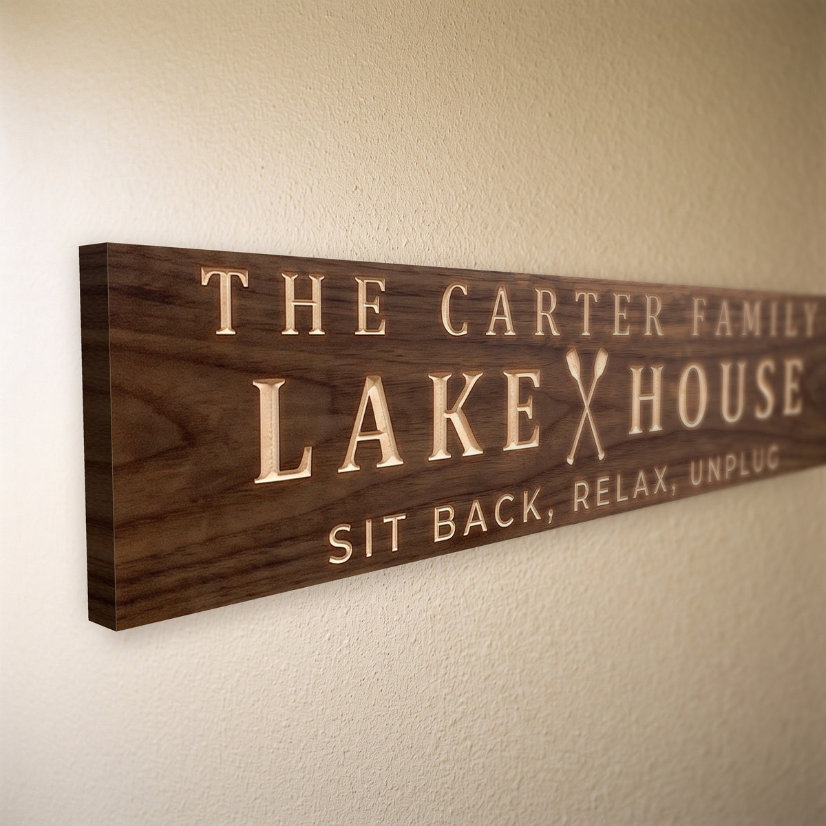 Close-up of the carved letters on the The Carter Family Lake House sign, natural pine inside the cuts against the stained grain