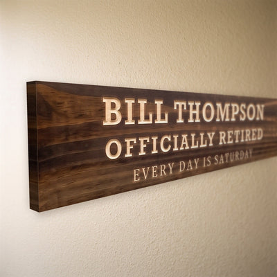 Close-up of the carved letters on the Bill Thompson sign, natural pine inside the cuts against the stained grain