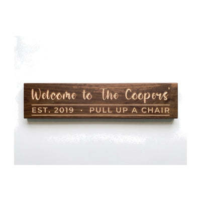 Personalized Welcome to The Coopers' sign carved into solid wood in a Dark Walnut finish, straight on, on a white background (studio photo)