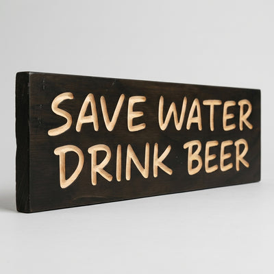 An angled view of the dark stained Save Water Drink Beer Sign shows its thickness and carved light wood letters