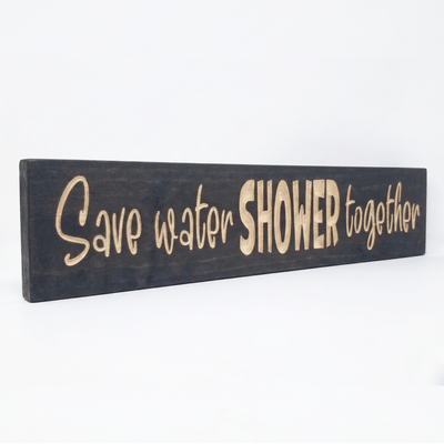 Angled view of the solid wood Save Water Shower Together couples bathroom wall art.
