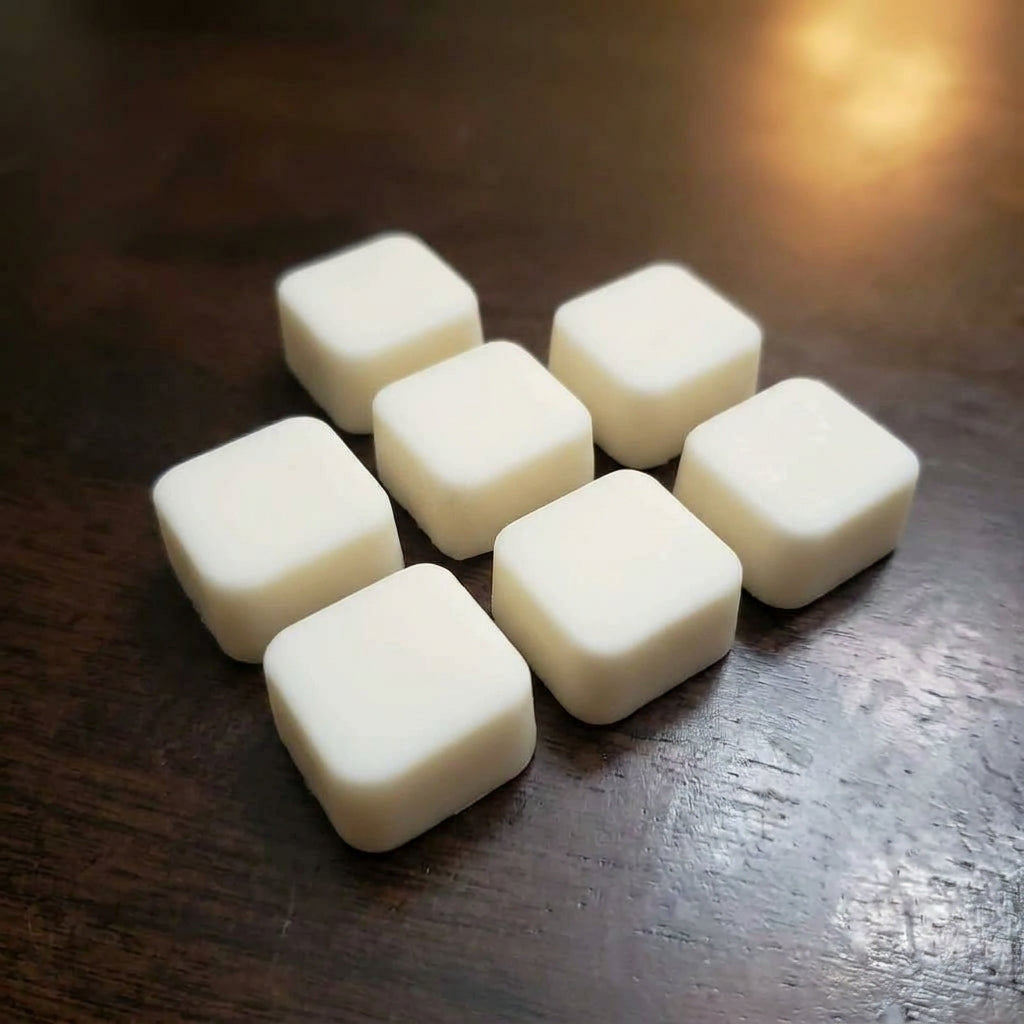 A small group of cream rounded square wax melts on a dark wood table