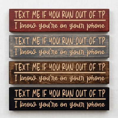 Four Text Me If You Run Out of TP CNC-carved bathroom signs stacked to show stain options including Cabernet, Carbon Gray, Dark Walnut, and Ebony