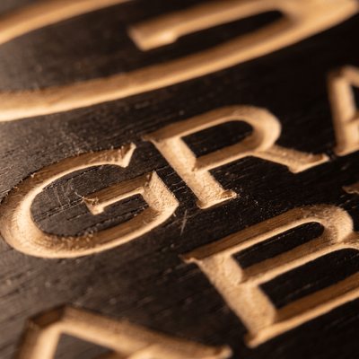 Close-up macro of deeply CNC-carved letters on the TGIF This Grandma Is Fabulous solid wood sign showing dimensional 2.5D routing detail