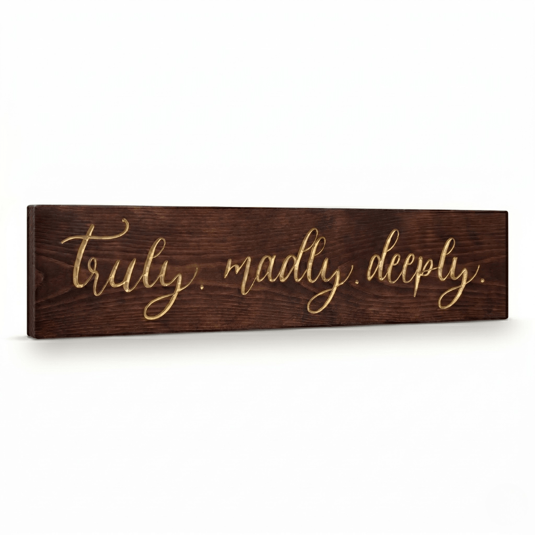 Angled side view of the Truly Madly Deeply carved wood sign showing the dimensional 2.5D depth of the gold script calligraphy on Dark Walnut