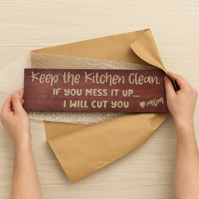 A person unboxing a funny wooden kitchen sign, revealing it as a unique housewarming or Mother's Day gift for a mom with a sense of humor.