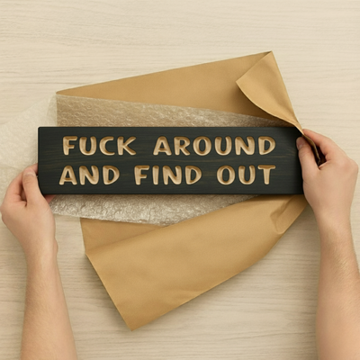 A person unboxing a dark "Fuck Around and Find Out" wood sign, showing it carefully packaged, highlighting it as a great gift idea.