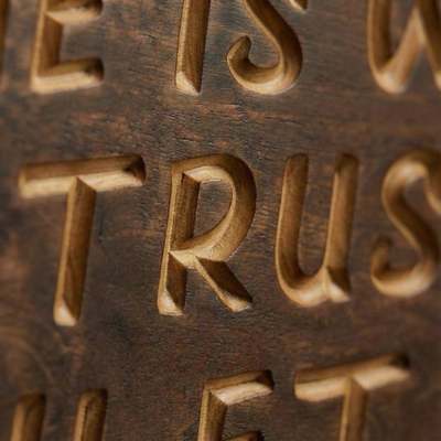 Extreme close-up detail of V-carved typography on a wooden sign showing the natural wood grain contrast against the dark stain.