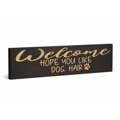 Angled view of Welcome Hope You Like Dog Hair wood sign showing carved lettering and natural finish
