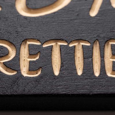 Macro close-up of CNC-carved my pretties letters revealing natural pine beneath the black finish.