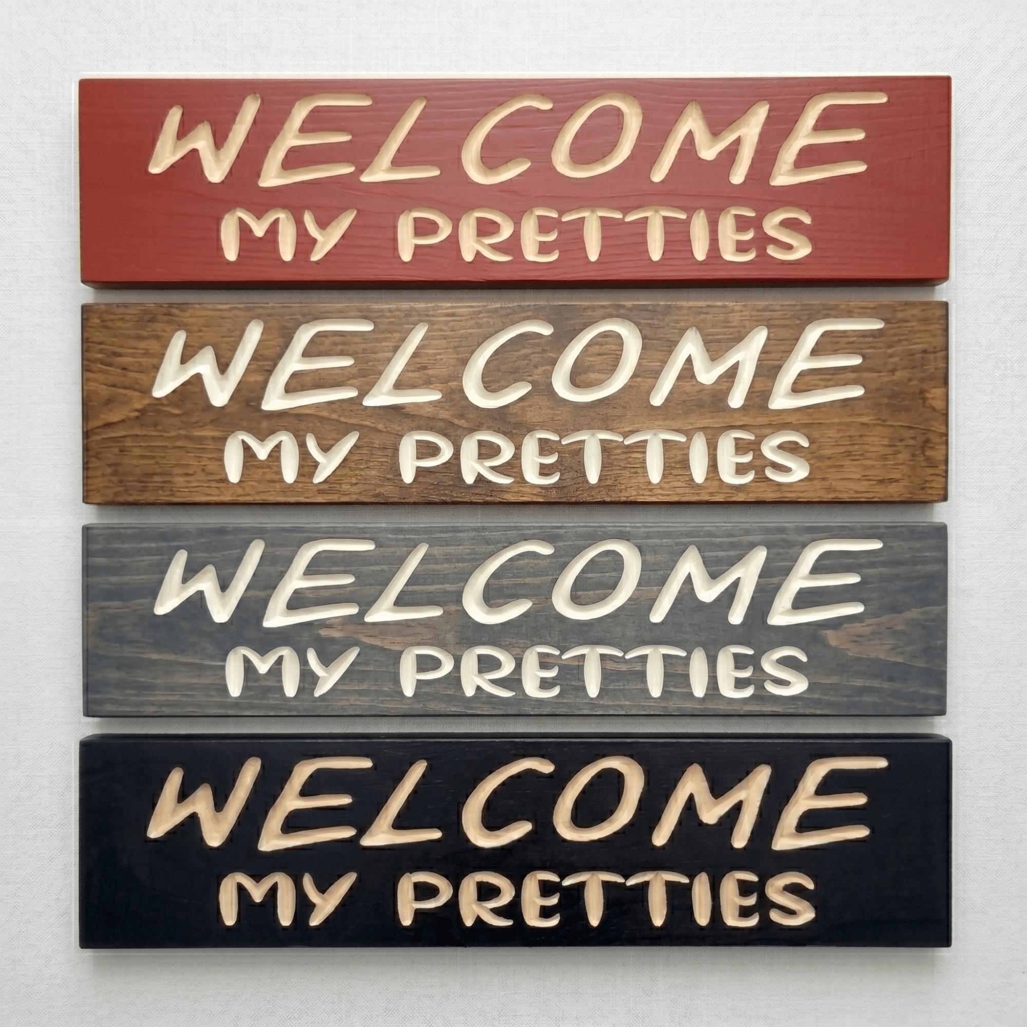 Four Welcome My Pretties Halloween signs in barn red, walnut, gray, and black finishes.