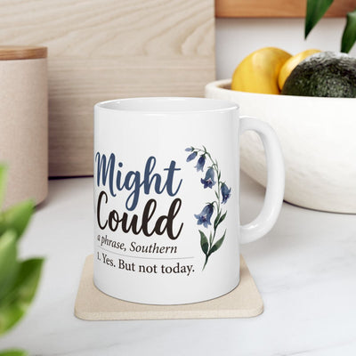 The white Mug With Sayings, featuring the "Might Could" phrase, rests on a light coaster in a modern kitchen setting