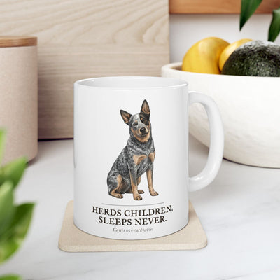 A Dog Mom Mug with a cattle dog design rests on a light coaster on a kitchen counter with fruit and greenery nearby