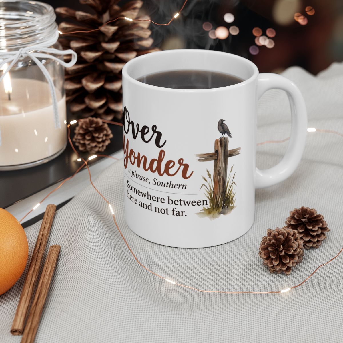 A Country Coffee Mug filled with dark liquid, surrounded by pine cones and a candle, creating a cozy autumn scene