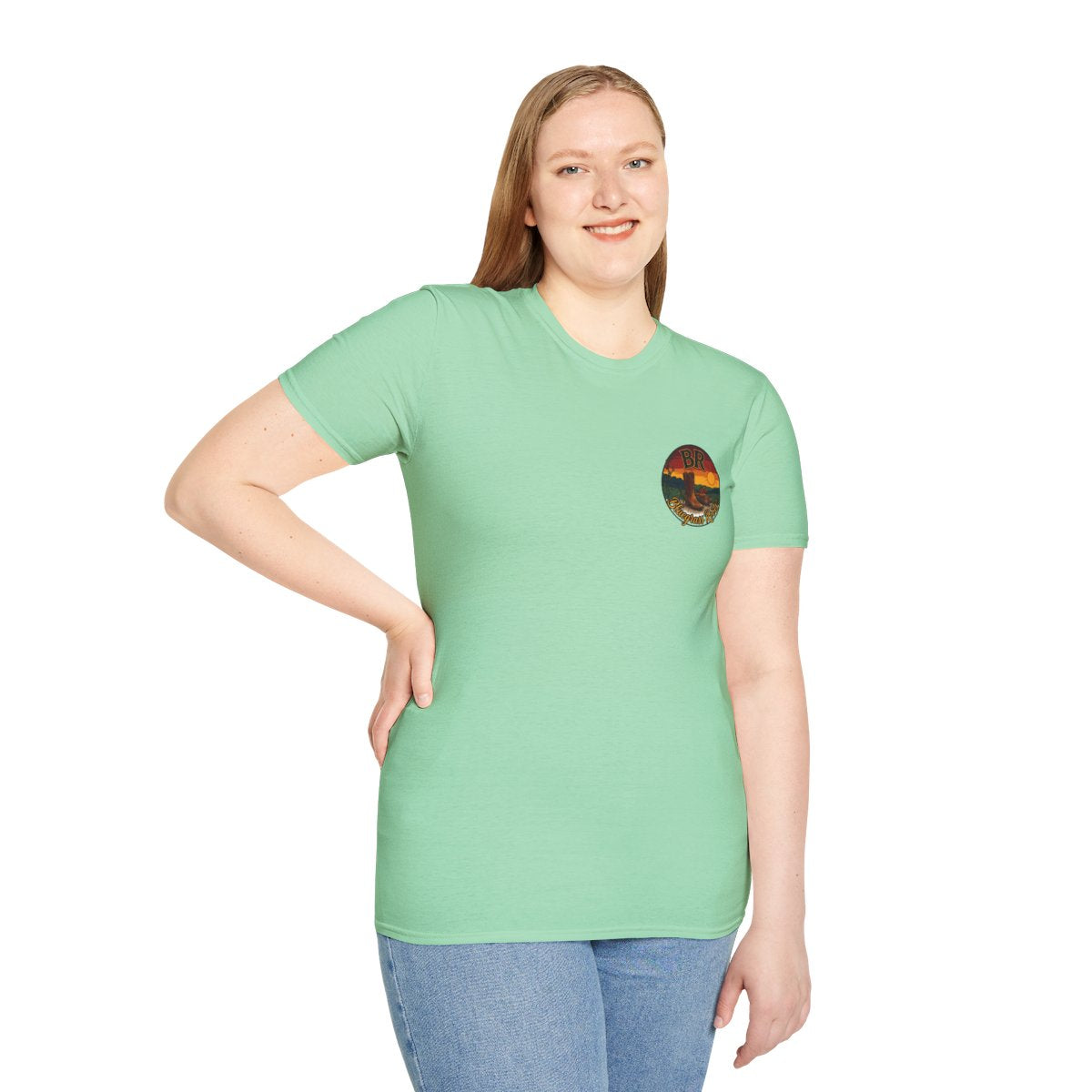 A woman in jeans smiles, looking forward, wearing the mint green Y'all Shirt with the small circular logo on the chest
