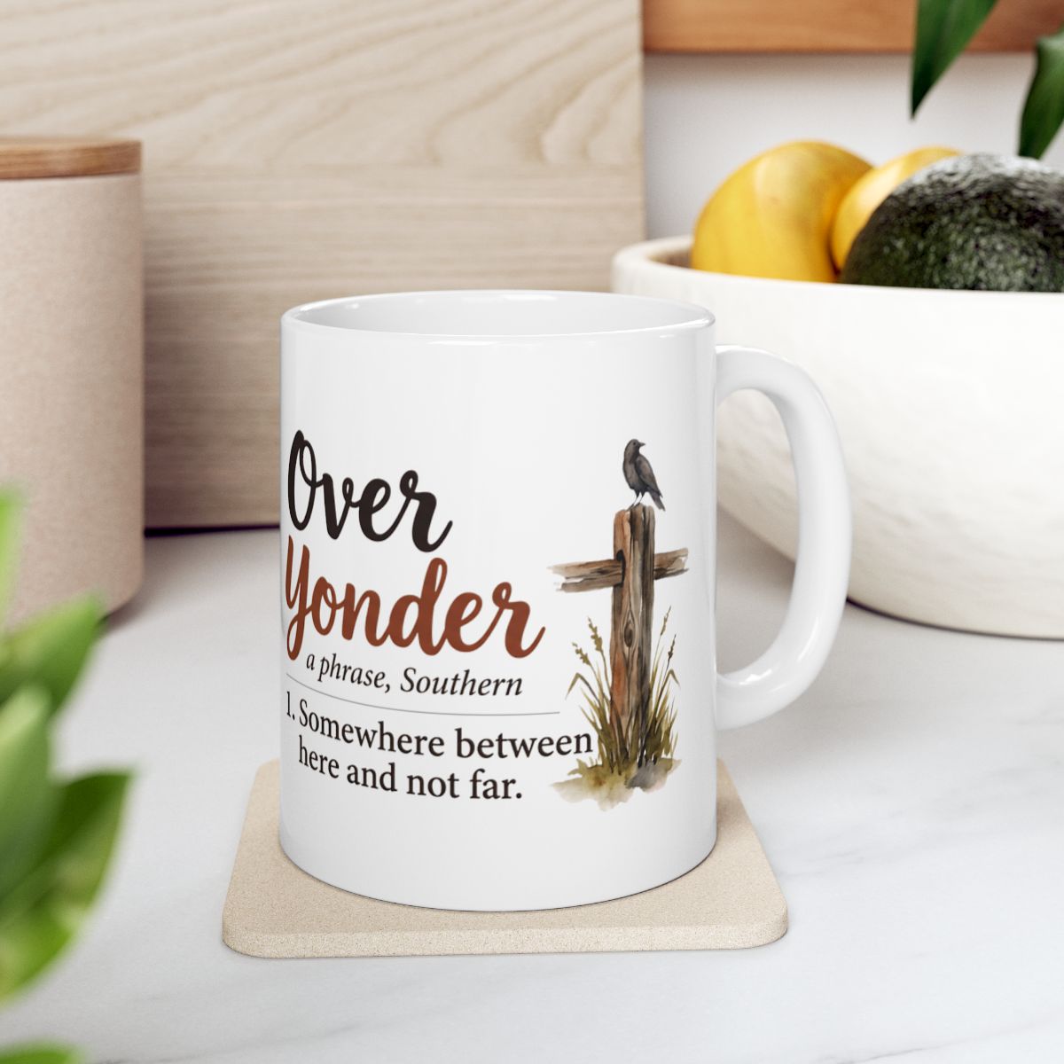 A white Country Coffee Mug with the "Over Yonder" design sits on a light-colored coaster in a bright kitchen setting