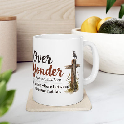 A white Country Coffee Mug with the "Over Yonder" design sits on a light-colored coaster in a bright kitchen setting