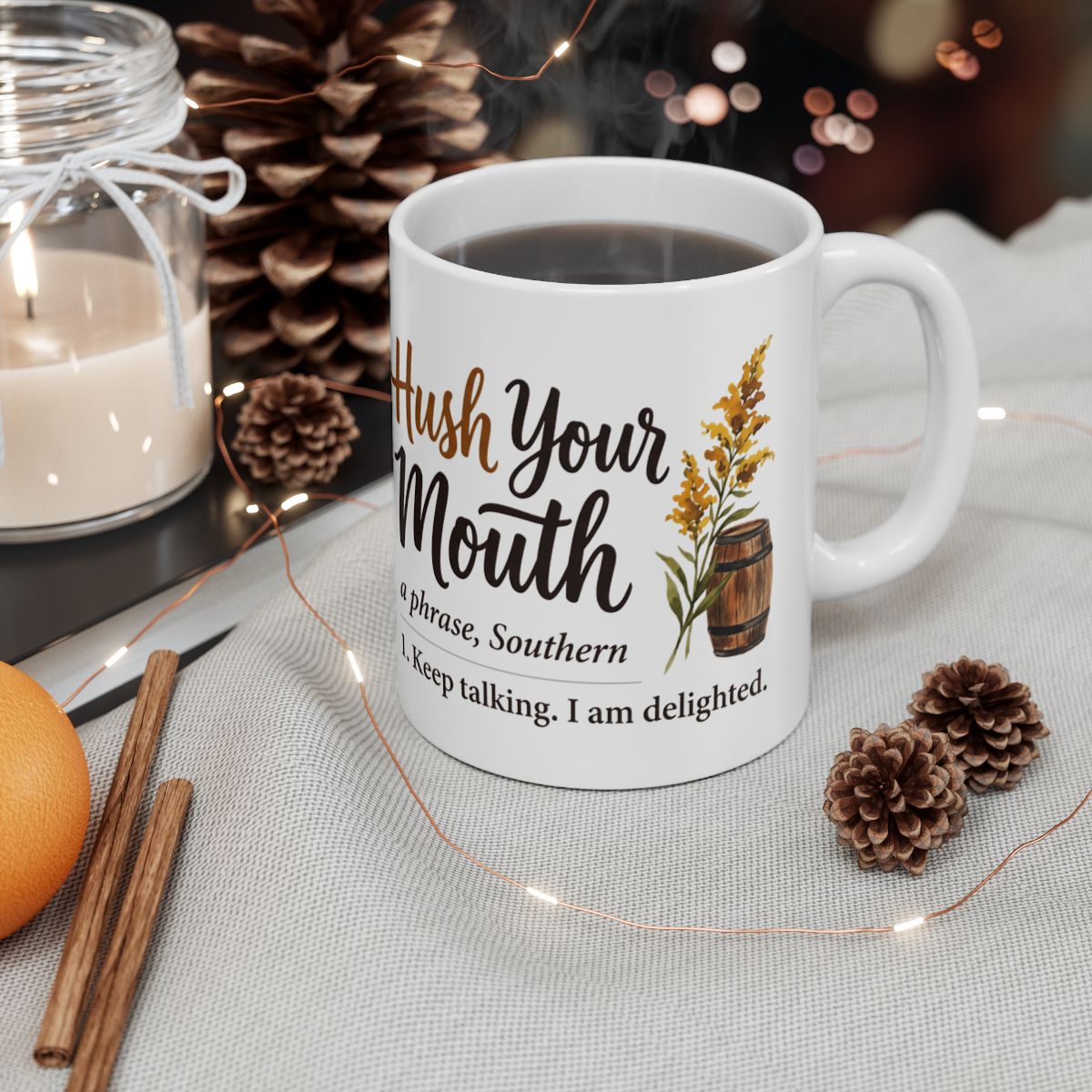 A Kentucky Coffee Mug filled with dark liquid sits on a festive table with pinecones, string lights, and a candle
