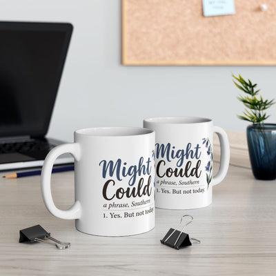 Two white Mug With Sayings are displayed on a desk, one in front of the other, near a laptop and office supplies
