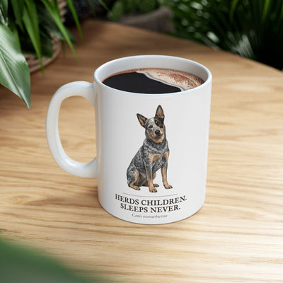 A white Dog Mom Mug, full of coffee, is placed on a wooden table with a green plant in the soft background