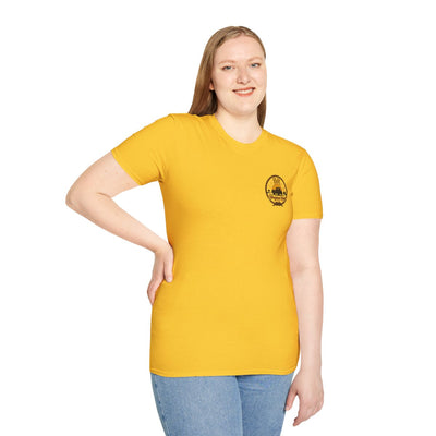 A woman with long hair poses with one hand on her hip, wearing the yellow Raised Right Shirt, looking at the camera