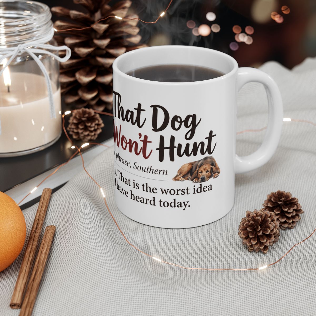A white Coffee Mug filled with dark liquid, surrounded by pinecones and a lit candle in a cozy setting