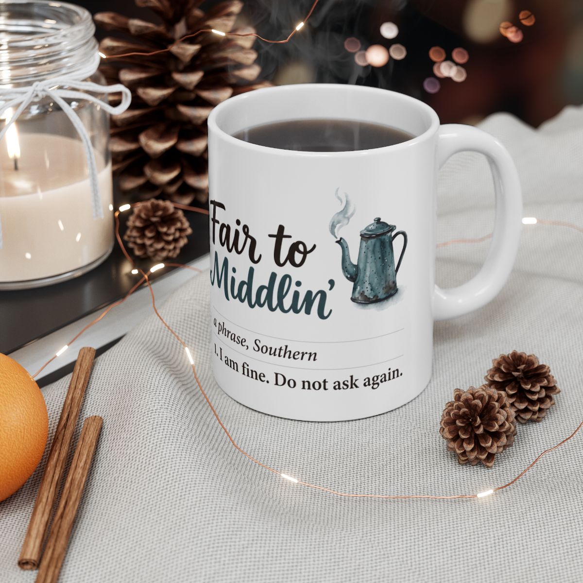 A steaming "Fair to Middlin'" Coffee Mug Gift with pinecones, cinnamon sticks, and a candle in a cozy setting
