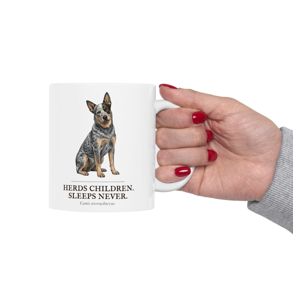 A hand with red painted nails holds the white Dog Mom Mug, featuring the dog graphic and humorous text prominently