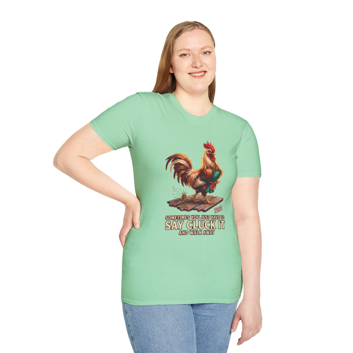 A woman standing with a hand on her hip, wearing a light green 'Chicken Shirt - Sometimes You Just Have to Say Cluck It' tee